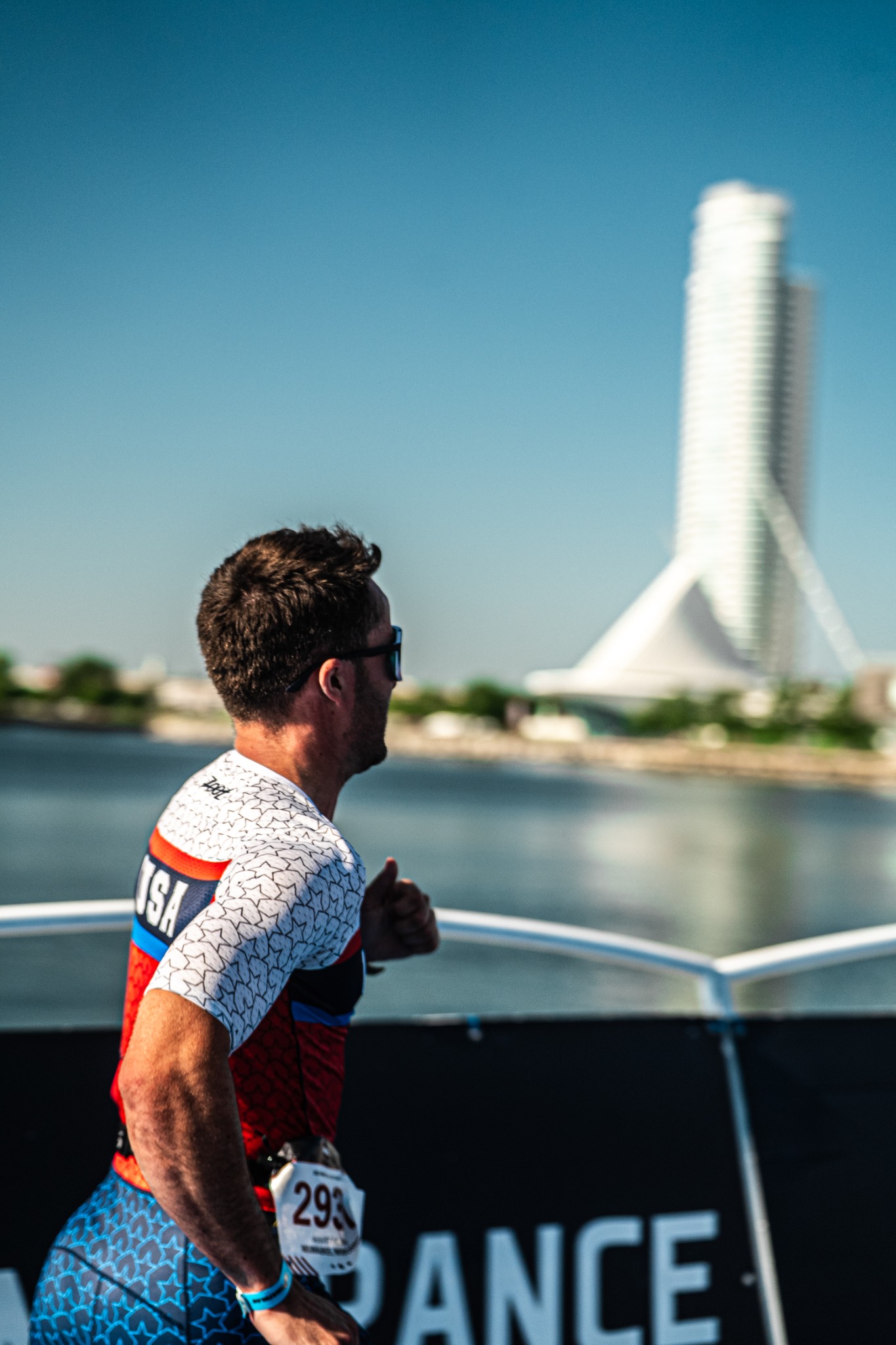 Triathlete running beside the water with a city landmark in the distance